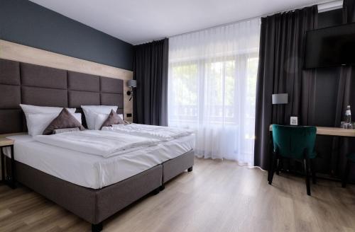 a bedroom with a large bed and a desk and window at Waldhotel Wandlitz in Wandlitz