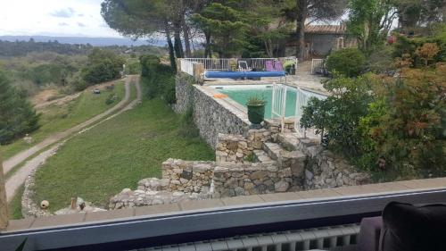 a house with a stone wall and a swimming pool at Mas la Rocaille in Clermont-lʼHérault