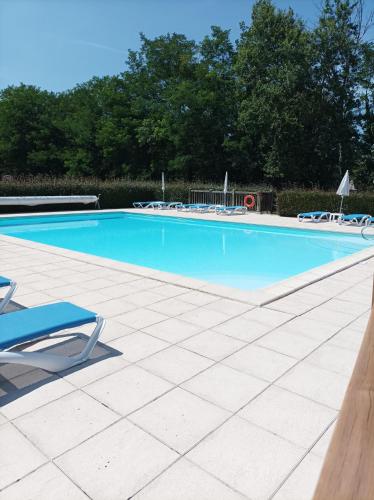 une grande piscine bleue avec des chaises et des arbres dans l'établissement Au pied de la Dordogne, à Argentat