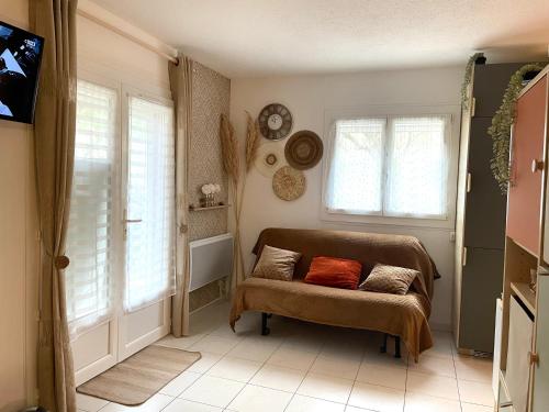 ein Wohnzimmer mit einer Couch und zwei Fenstern in der Unterkunft La Bandolaise, studio 25m2 in Bandol