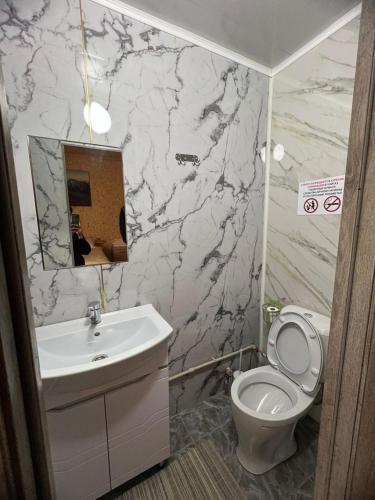 a bathroom with a white toilet and a sink at Zhyluu Suu Resort BozUchuk in Novovoznesenovka