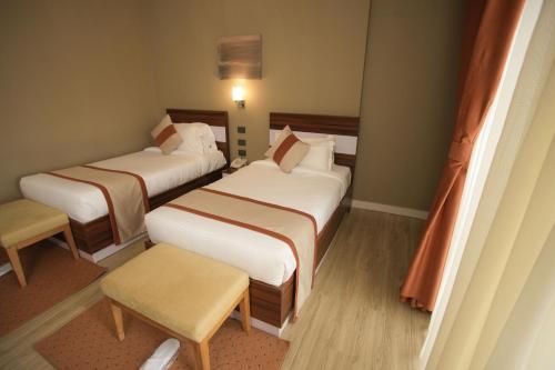 a hotel room with three beds and a chair at Haile Hotel Wolaita in Sodo