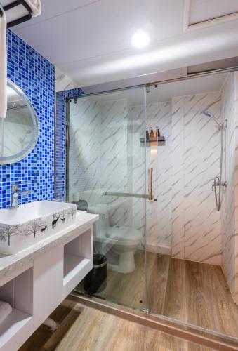 a bathroom with a glass shower and a toilet at Qingdao Liuying Jieli Hotel - Qingdao Station Trestle Bridge Branch in Qingdao