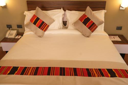 a large white bed with pillows and a phone at Haile Hotel Wolaita in Sodo