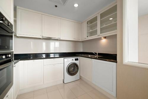 a kitchen with white cabinets and a washing machine at Grande Centre Point Hotel Ratchadamri Bangkok in Bangkok