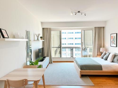 a white bedroom with a bed and a large window at Atlantic Suites Serviced Apartments in Gibraltar