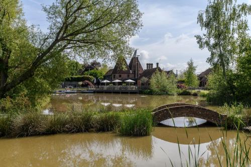 a bridge over a river in front of a building at Vineyard Oast Sleeps 25 in Wavehorne