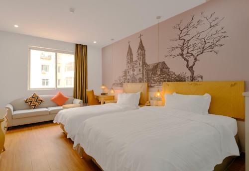 a hotel room with two beds and a couch at Qingdao Liuying Jieli Hotel - Qingdao Station Trestle Bridge Branch in Qingdao