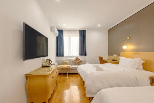 a hotel room with two beds and a television at Qingdao Liuying Jieli Hotel - Qingdao Station Trestle Bridge Branch in Qingdao