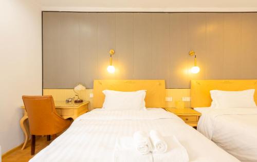 a hotel room with two beds with towels on them at Qingdao Liuying Jieli Hotel - Qingdao Station Trestle Bridge Branch in Qingdao