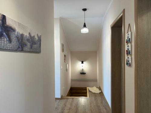 a hallway with white walls and wood floors and a light fixture at Lotus Retreat in Ghermăneşti