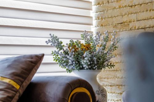 a white vase filled with flowers sitting on a couch at Ge-Lux in Inceşti