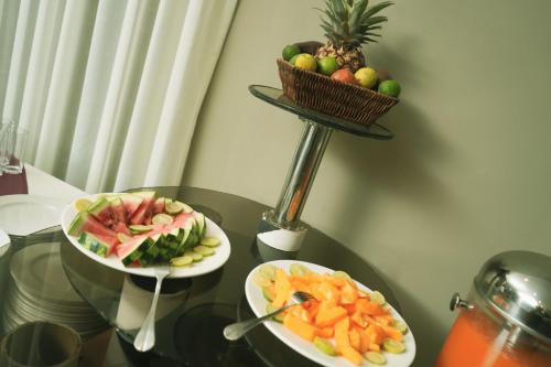two plates of fruit on a glass table with a basket of fruit at Haile Hotel Wolaita in Sodo