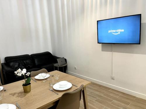 a living room with a table and a flat screen tv at 736 Agréable studio mezzanine proche de Paris 20 in Bagnolet