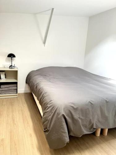 Ce lit se trouve dans une chambre blanche dotée d'un canapé-lit. dans l'établissement 736 Agréable studio mezzanine proche de Paris 20, à Bagnolet