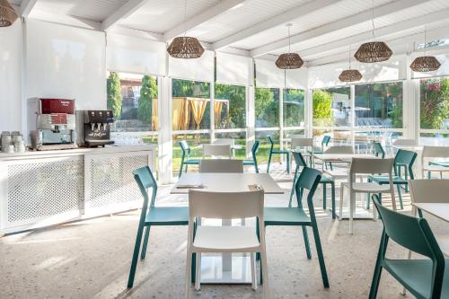 a restaurant with tables and chairs and windows at Hotel Vibra Isola - Adults only in Playa d'en Bossa