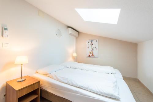 a white bedroom with a bed and a table at Villa Agape in Sampzon