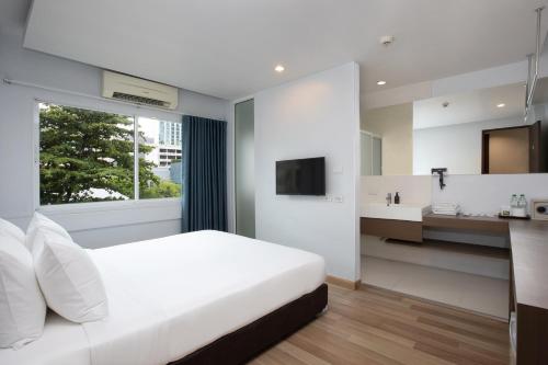 a white bedroom with a large bed and a sink at Nantra Silom in Bangkok