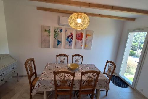 a dining room with a table with chairs and a chandelier at Sous le Grand Pin Piscine & Spa Gîtes Éden en Cévennes à Anduze Gard in Anduze