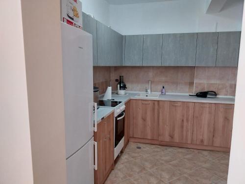 a kitchen with a white refrigerator and wooden cabinets at ГЪРБИЩЕ ЕКОТУР - къща за гости in Yabulkovets