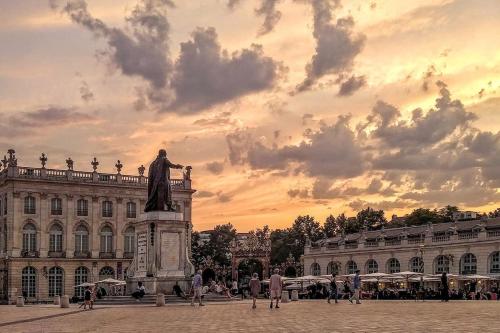 a statue in front of a building with a sunset at La bulle urbaine in Nancy