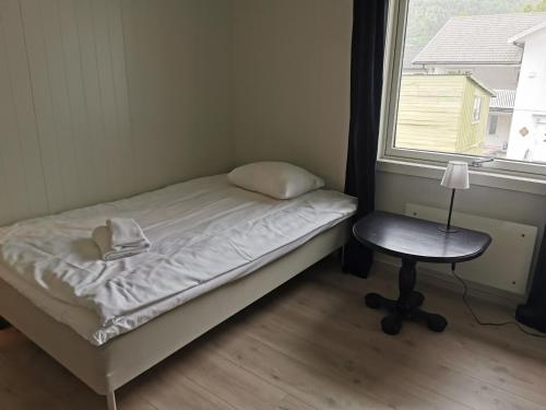 a bed and a chair in a room with a window at Mosjøen Overnatting, Tordenskjolds gate 24b in Mosjøen