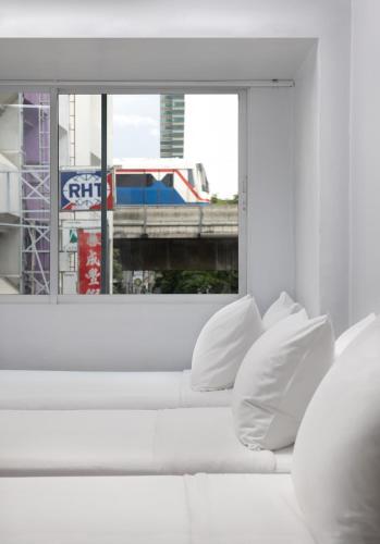 a white couch in a room with a window at Nantra Silom in Bangkok