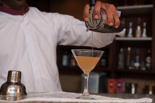 a man is pouring a drink into a glass at Haile Hotel Wolaita in Sodo