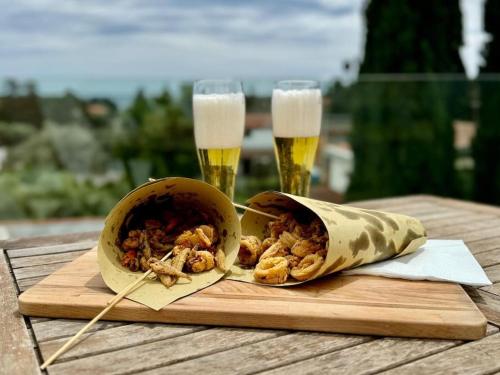 A window into the blue في كوارتو سانت إيلينا: وعاء من الطعام على طاولة خشبية مع كوبين من البيرة