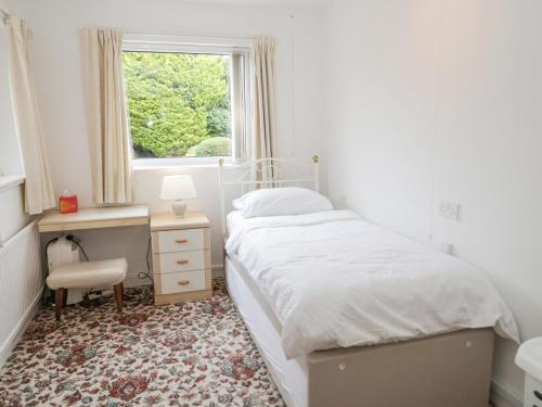 a white bedroom with a bed and a window at Breve Rest in Abergele