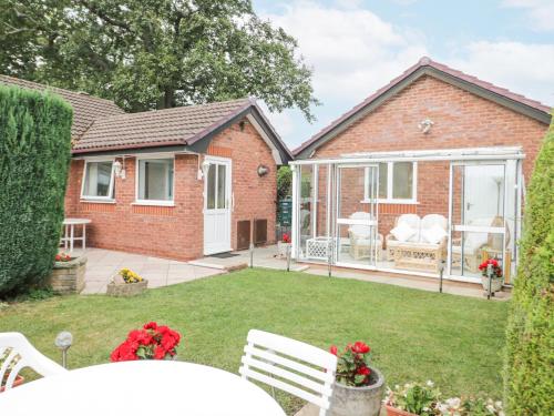 a garden with a conservatory and a house at Breve Rest in Abergele