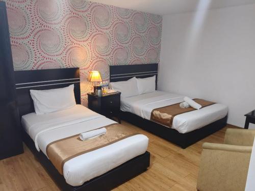 a hotel room with two beds and a chair at Bluebell Hotel skudai in Kempas
