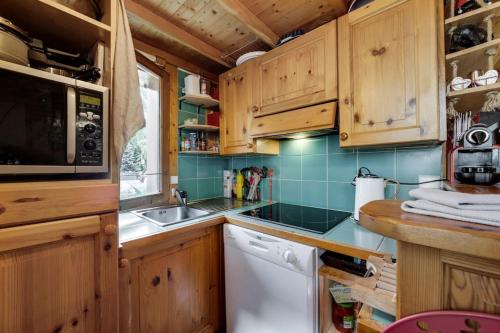 a kitchen with wooden cabinets and a white dishwasher at Chalet Barme de l'Ours 1 in Val dʼIsère