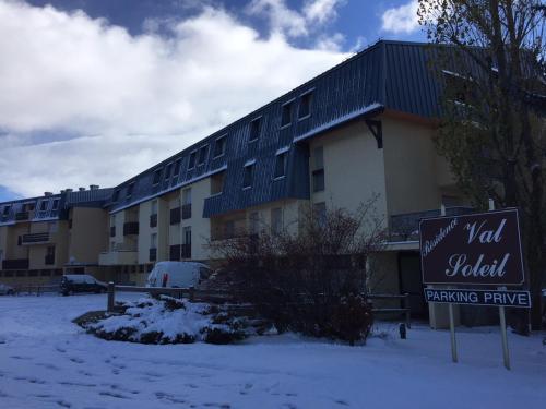 a building with a sign in front of it in the snow at Les Appartements Du Père Castor-Self Check-In in Font-Romeu-Odeillo-Via