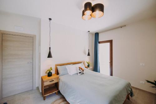 a bedroom with a white bed with a wooden night stand at Casa Emilia B&B with cocktail bar in Albinea
