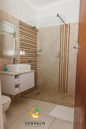 a bathroom with a shower and a sink and a toilet at Sunpalm Guesthouse in Nelspruit