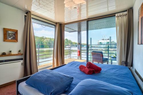 a bedroom with a blue bed with a large window at HouseBoat - Une maison sur l'eau in Conflans-Sainte-Honorine