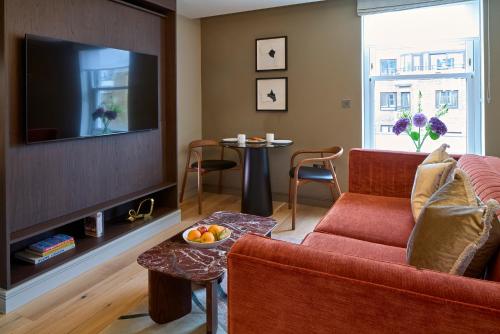 a living room with a red couch and a tv at Cheval Phoenix House at Sloane Square in London