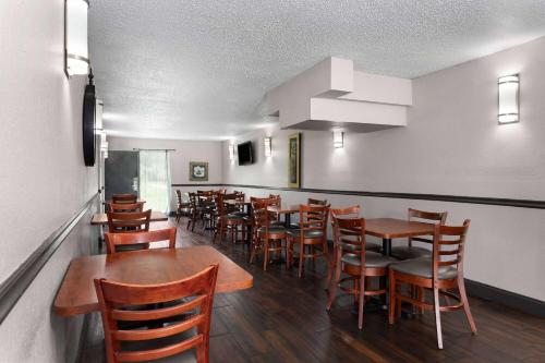 una sala da pranzo con tavoli e sedie in legno di Days Inn by Wyndham Wildwood I-75 a Wildwood