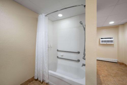 a bathroom with a shower and a white tub at Days Inn & Suites by Wyndham Bozeman in Bozeman