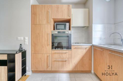 - une cuisine avec des placards en bois et un four micro-ondes dans l'établissement Le Clairsemé - En bordure de Paris - 364B, à Issy-les-Moulineaux