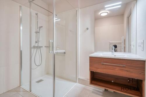 une salle de bain blanche avec une douche et un lavabo dans l'établissement Le Clairsemé - En bordure de Paris - 364B, à Issy-les-Moulineaux