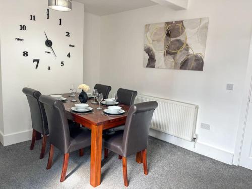 a dining room table with chairs and a clock on the wall at 8 Nantwich Road in Crewe
