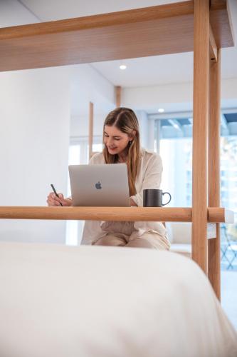 a woman sitting in front of a laptop computer at Seaside 8 l Aparthotel 50m from the Promenade in Cape Town
