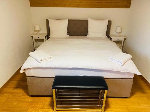 a bed with white sheets and a stool in a room at Lake View Residence in Niederried