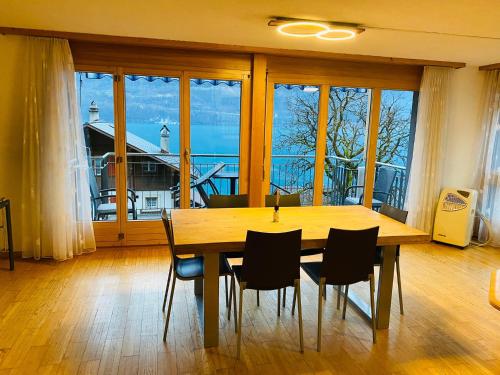 a dining room table with chairs and a large window at Lake View Residence in Niederried