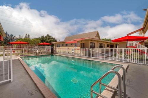 a swimming pool at a resort with red umbrellas at Fort Lauderdale Gardens Inn & Suites Ft Lauderdale International Airport in Hollywood