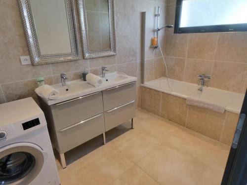 La salle de bains est pourvue d'un lavabo, d'une baignoire et d'un lave-linge. dans l'établissement Villa spacieuse avec piscine, secteur très calme, à Nîmes