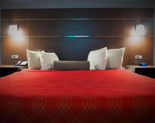 a bedroom with a red bed with white pillows at Econo Lodge Augusta West near Fort Eisenhower in Augusta