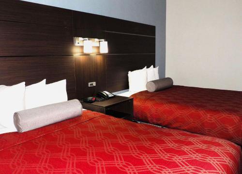 two beds in a hotel room with red sheets at Econo Lodge Augusta West near Fort Eisenhower in Augusta